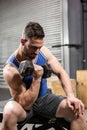 Muscular man sitting on bench lifting dumbbell Royalty Free Stock Photo