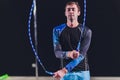 Muscular man skipping rope. Portrait of muscular young man exercising with jumping rope on black background.