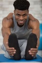 muscular man stretching forward and holding feet