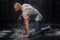 Muscular man under the rain in studio. Sexy male in water drops Royalty Free Stock Photo