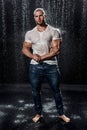 Muscular man under the rain in studio. Sexy male in water drops Royalty Free Stock Photo