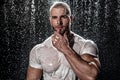 Muscular man under the rain in studio. Sexy male in water drops Royalty Free Stock Photo