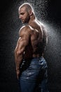 Muscular man under the rain in studio. Sexy male in water drops Royalty Free Stock Photo