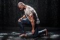 Muscular man under the rain in studio. Sexy male in water drops Royalty Free Stock Photo