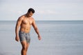 Muscular model young man walking on sea shore. asia man feeling relax on beach summer vacation Royalty Free Stock Photo