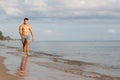 Muscular model young man walking on sea shore. asia man feeling relax on beach summer vacation Royalty Free Stock Photo