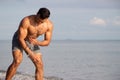 Muscular model young man walking on sea shore. asia man feeling relax on beach summer vacation Royalty Free Stock Photo