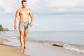 Muscular model young man walking on sea shore. asia man feeling relax on beach summer vacation Royalty Free Stock Photo