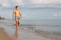 Muscular model young man walking on sea shore. asia man feeling relax on beach summer vacation Royalty Free Stock Photo