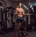 Muscular shirtless bodybuilder male lifting a barbell on a biceps in a gym. Royalty Free Stock Photo