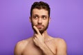 Muscular shirtless man is unsure, holding chin with finger Royalty Free Stock Photo