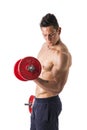 Muscular shirtless young man exercising biceps