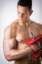 Muscular shirtless young man exercising biceps