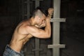 Muscular shirtless young man resting against metal column