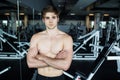 Muscular, shirtless young man resting in gym during workout, showing muscular torso, pecs and abs in the mirror at gym