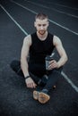 Muscular slender man in training at the stadium drinks water from a sports shaker. recreation sports. athletic exercising