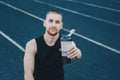 Muscular slender man in training at the stadium drinks water from a sports shaker. recreation sports. athletic exercising