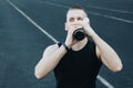 Muscular slender man in training at the stadium drinks water from a sports shaker. recreation sports. athletic exercising