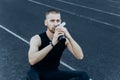 Muscular slender man in training at the stadium drinks water from a sports shaker. recreation sports. athletic exercising