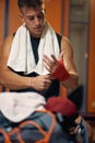 Muscular sporty young man tying red protective tape around hands for boxing