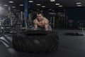 Muscular,Strong bodybuilder pushing tire in modern fitness cente