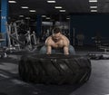 Muscular,Strong bodybuilder pushing tire in modern fitness cente