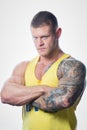 Muscular strong shredded man with blue eyes and tattoo in the yellow tank top the white background Royalty Free Stock Photo