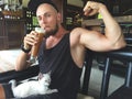 Muscular Strong Vegan Man Showing Biceps and Drinking Iced Coffee Protein Drink. Cute Small Kitten Sitting on Sportsman Royalty Free Stock Photo