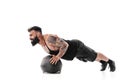 Muscular tattooed bearded male exercising fitness weights Medicine Ball push ups exercises in studio isolated on white