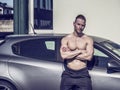 Muscular topless man outside of car