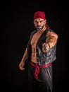 The Pirate, A Male Bodybuilder with a Red Bandanna Standing Proudly Before a Black Canvas