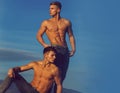 Muscular torsos with six packs pose outdoors on sky. Sexy muscular men. Concept of the twins. Two twin brothers with