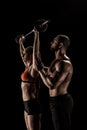 Muscular trainer looking at young sportswoman lifting barbell Royalty Free Stock Photo