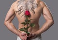 Bare tattooed man hiding flower