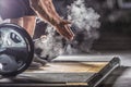 Muscular weightlifter clapping hands before barbell workout at the gym with dumbbells