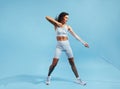 Muscular woman exercising with elastic band. Female in fitnesswear pulling resistance band on blue background