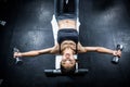 Muscular woman lifting dumbbell while sitting on bench Royalty Free Stock Photo