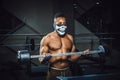 Muscular young african american man in mask lifting barbell on biceps. Exercise for biceps with barbell. black man in gym Royalty Free Stock Photo