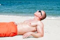 Muscular young athletic man lying on the beach Royalty Free Stock Photo