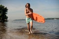 Muscular beach lifeguard running along the river bank with life-saving equipment