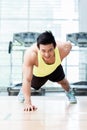 Muscular young man doing one armed pushups in gym