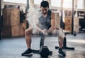 Im ready to rumble. a muscular young man dusting his hands with chalk powder while exercising with a dumbbell in a gym. Royalty Free Stock Photo