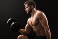 Muscular young man exercising with dumbbells