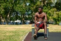Muscular young man exercising at the sports field. African man looking to the side while doing horizontal bar exercises