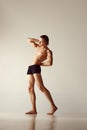 Muscular young man with fit healthy body standing shirtless in underwear against grey studio background. Flexibility Royalty Free Stock Photo