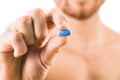 Muscular young man holding blue pill Royalty Free Stock Photo