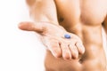 Muscular young man holding blue pill Royalty Free Stock Photo