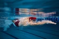 Muscular young man, swimmer in motion, preparing for competition, training in swimming pool indoors. Speed and technique Royalty Free Stock Photo