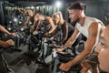 Muscular young men and women on cycling class at gym