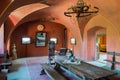 Museum exposition of a medieval room with a long dining table, high chairs and a decorative chandelier above them